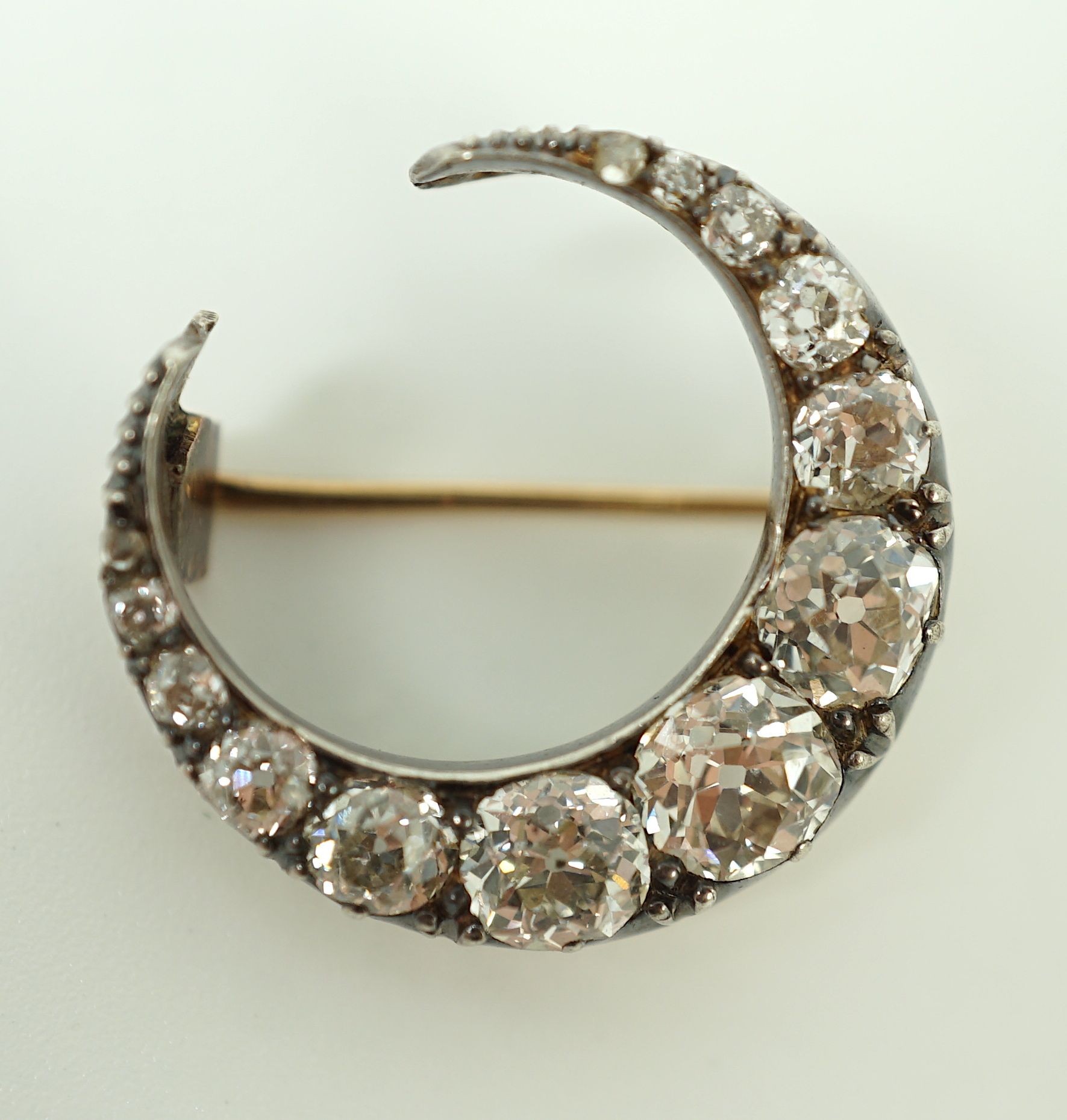 A Victorian gold, silver and graduated thirteen stone diamond set crescent brooch
